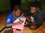A UNIPA community worker taught a local student reading at Womom village © S4C LPPM UNIPA/Hermina Langoday
